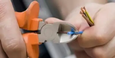 licensed electrician performing precise wire cutting and preparation during electrical service in Sarasota, FL