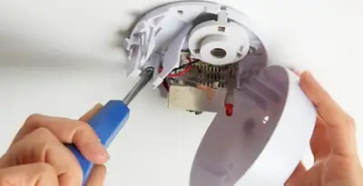 Certified technician wiring smoke detector during installation in Sarasota, FL